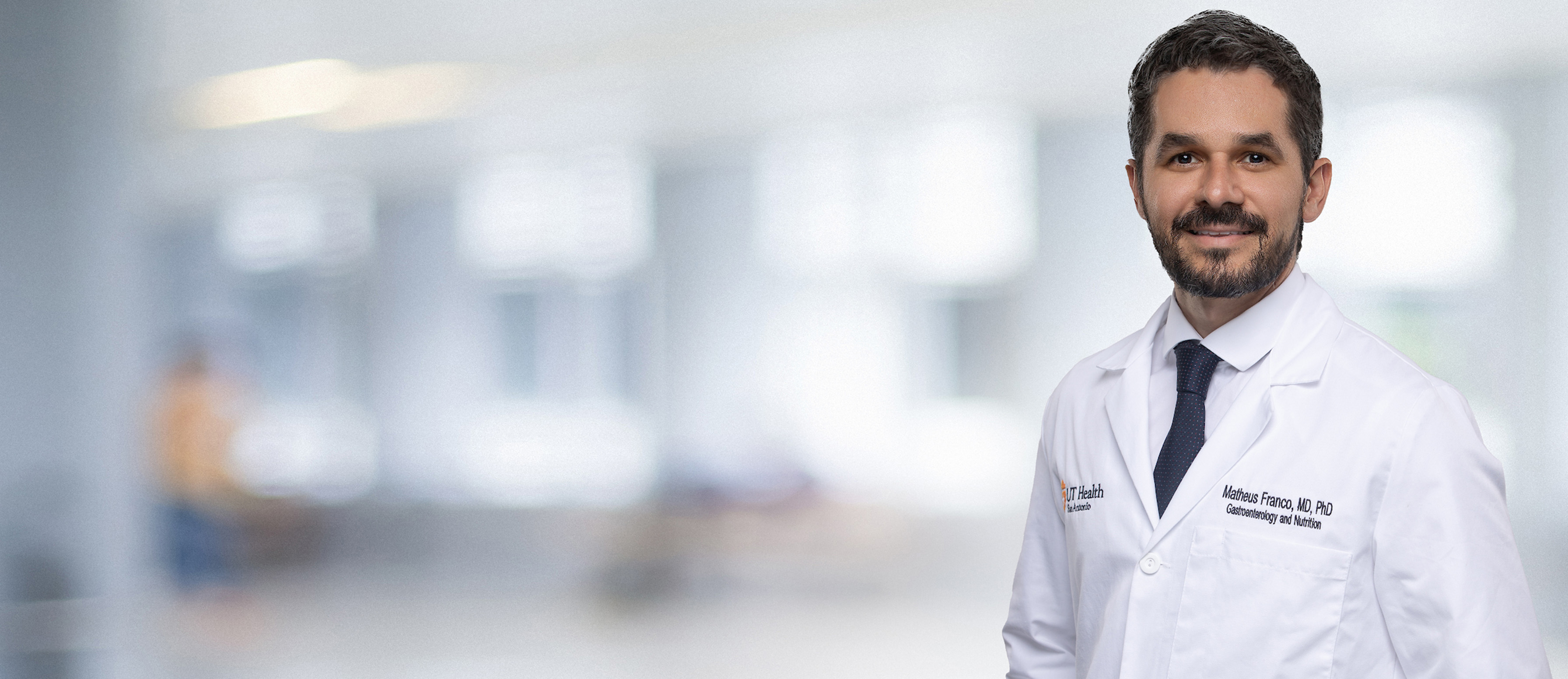 physician in white coat in front of lab background
