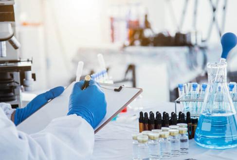 lab scene with gloved hands holding clipboard, test tubes and microscope in background